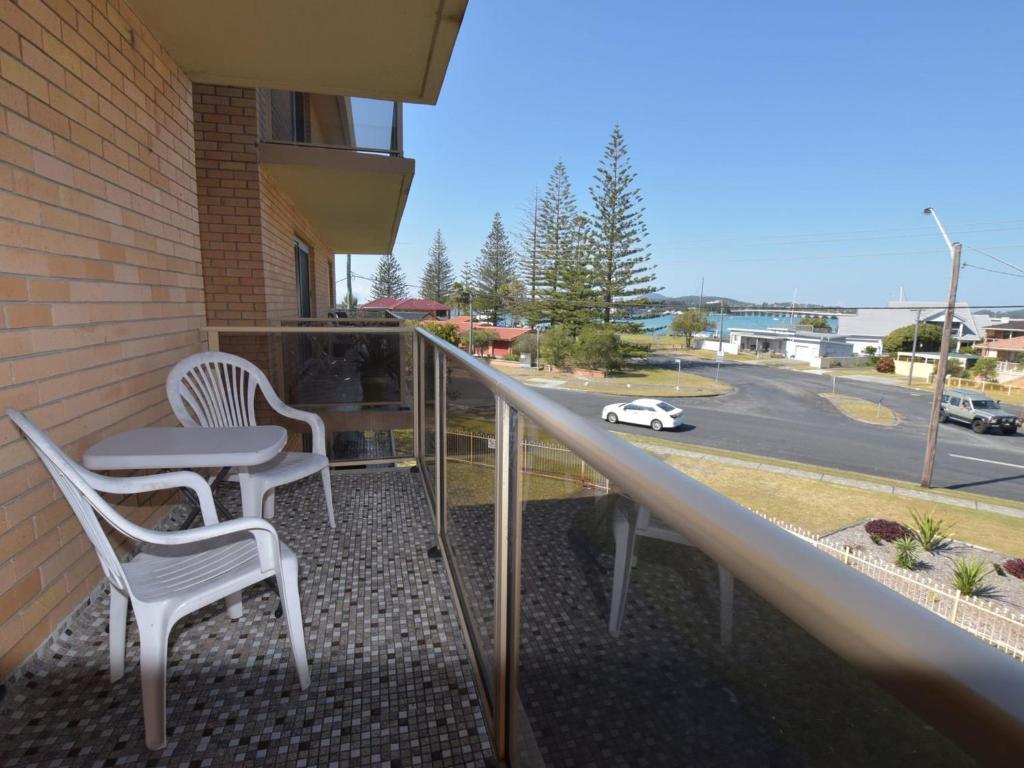 einen Balkon mit zwei Stühlen und einem Tisch und einem Auto auf einer Straße in der Unterkunft Anchorage 10 in Tuncurry