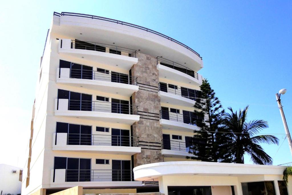 ein weißes Gebäude mit schwarzen Fenstern und einer Palme in der Unterkunft Topacio7 Residencial in Boca del Río