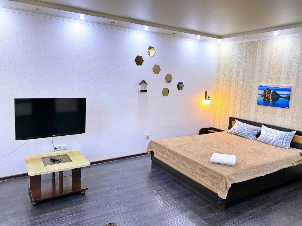 a bedroom with a large bed and a flat screen tv at Baykal Apartments on Dekabristov in Krasnoyarsk