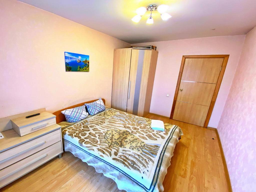 a small bedroom with a bed and a dresser at Baikal Apartments at Vzletka - Krasnoyarsk in Krasnoyarsk