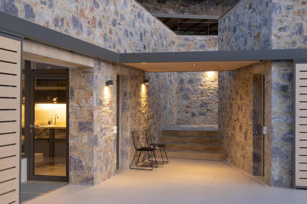 a lobby with stone walls and chairs and a table at Kechria Bay Villas in Skiathos
