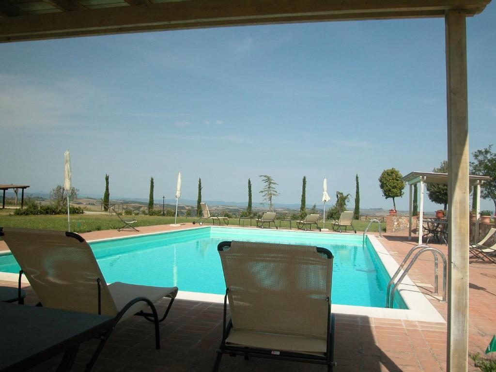 einen Pool mit 2 Stühlen und einem Tisch in der Unterkunft Villa with swimming pool, fenced, 10 bed places Toscana wi-fi in Serre di Rapolano