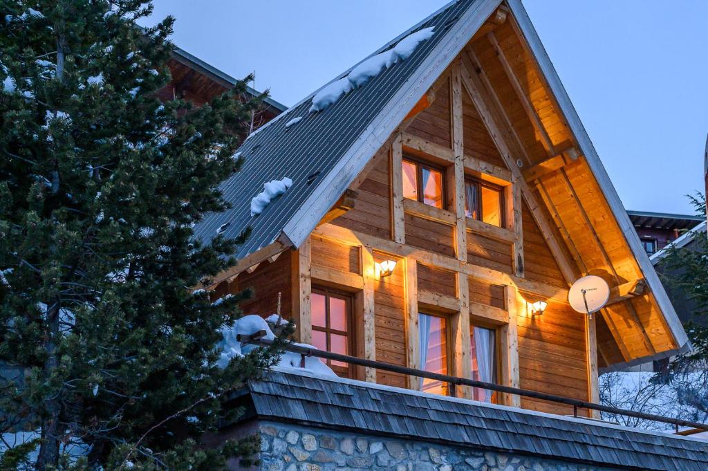Cette grande maison en bois dispose de fenêtres et d'un toit. dans l'établissement Petit Rochebrune, à Orcières