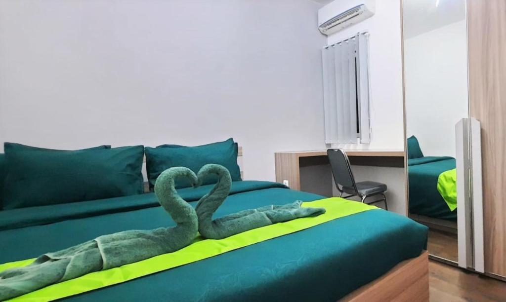 a bedroom with a green bed with two snakes on it at Nature's Room @ Aeropolis in Rawabambu