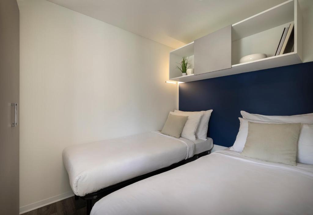 two beds in a small room with white and blue walls at Maistra Camping Valkanela Mobile homes in Funtana