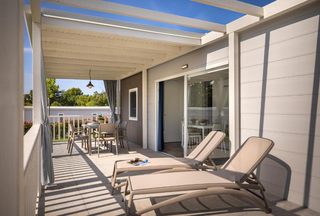 a porch with chairs and a table on a house at Maistra Camping Valkanela Mobile homes in Funtana
