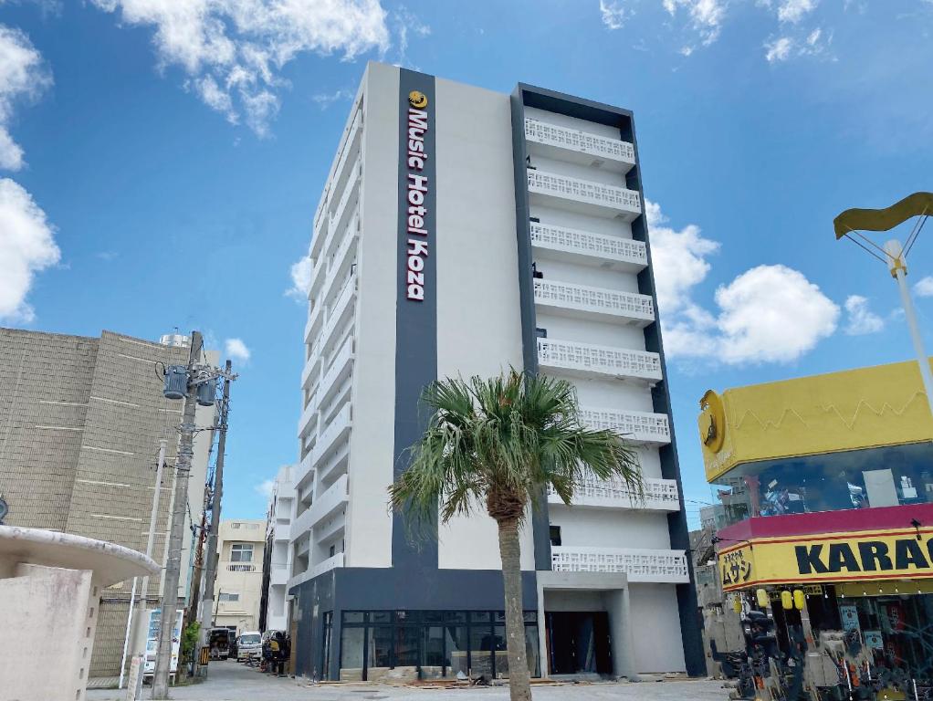 a tall building with a palm tree in front of it at Music Hotel Koza by Coldio Premium in Okinawa City