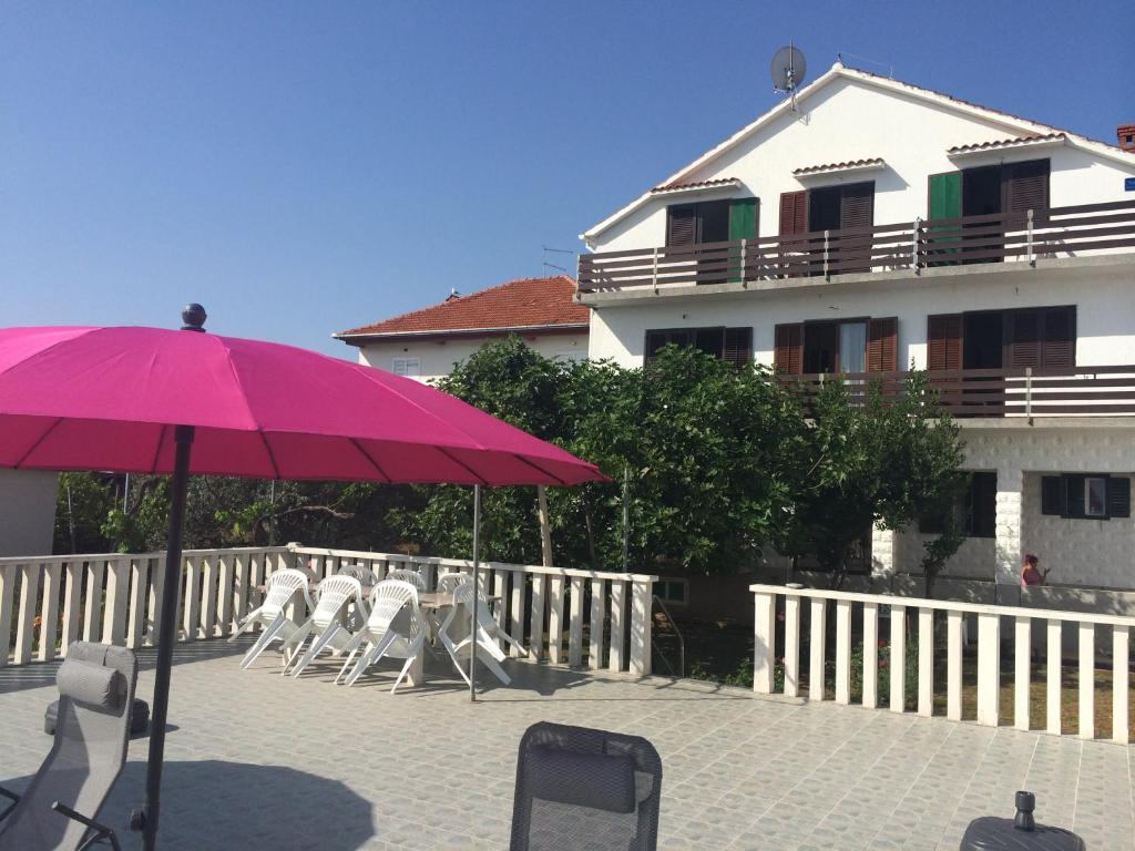 a pink umbrella and some chairs and a building at Guesthouse Lidija in Kukljica