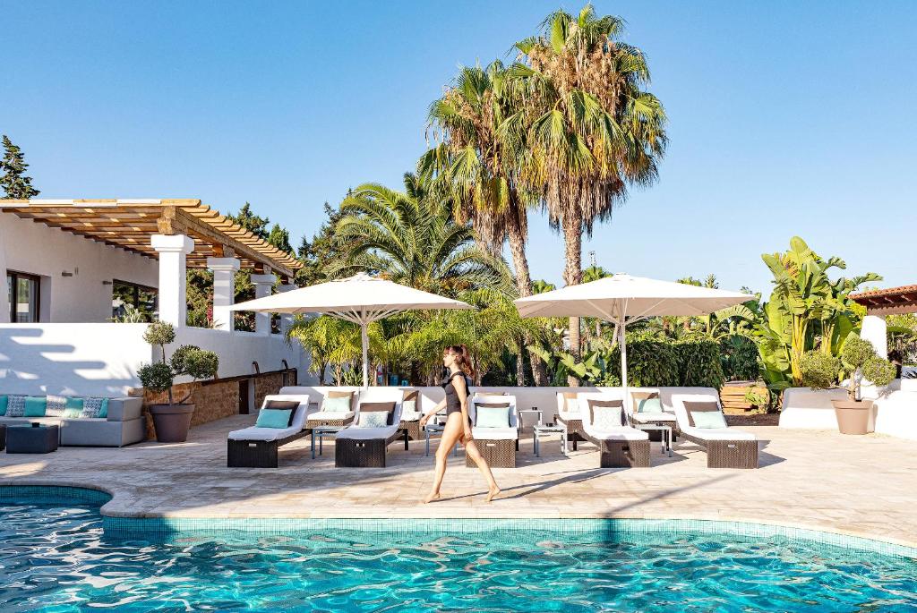 una mujer caminando por la piscina en un resort en Casa Munich, en Ses Salines