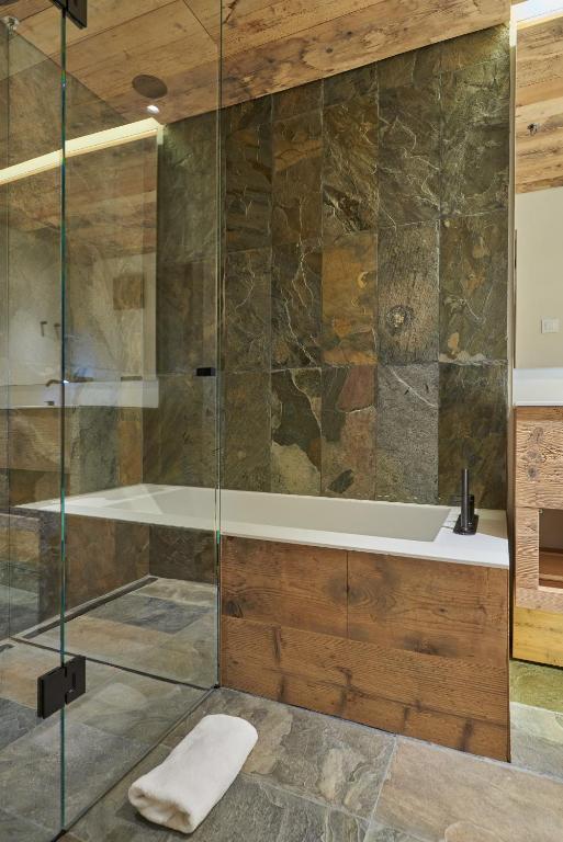 a bathroom with a glass shower with a tub at HOTEL de LEN in Cortina dʼAmpezzo