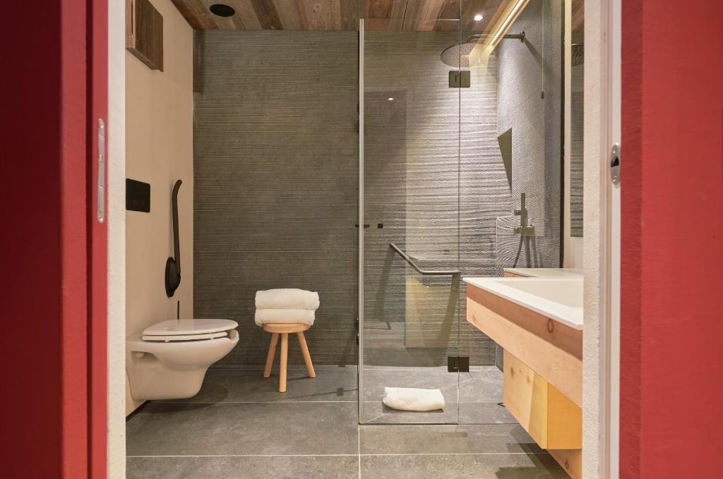 a bathroom with a toilet and a glass shower at HOTEL de LEN in Cortina dʼAmpezzo