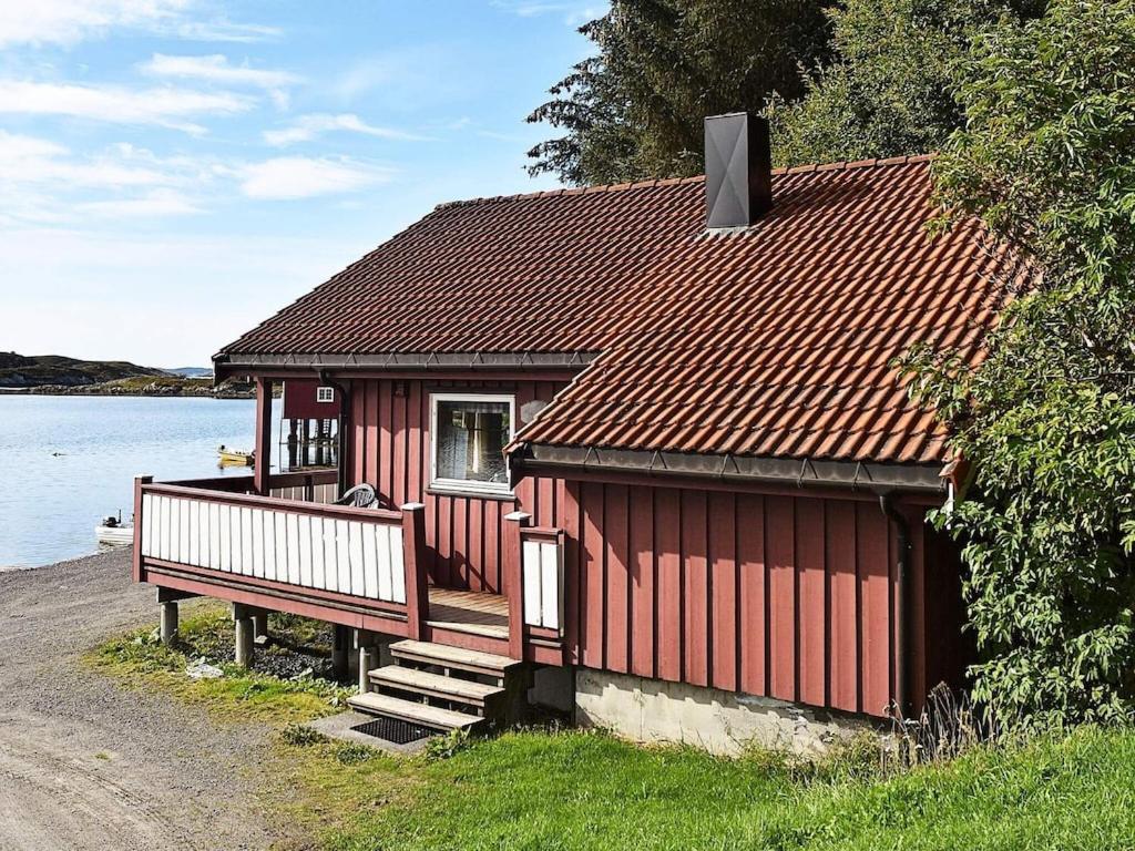 a red house with a bench next to a lake at 6 person holiday home in Bud-By Traum in Bud