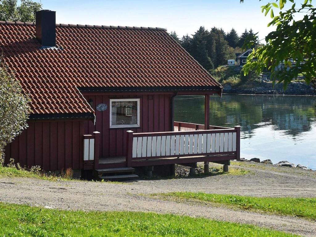 a small red building with a porch next to a lake at 6 person holiday home in Bud in Bud