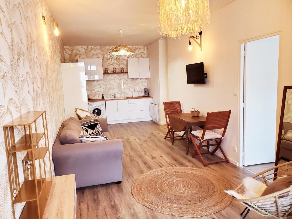 a living room with a couch and a table at "Le Rive-Gauche" appartement tout équipé, 2 chambres à 2 pas de la gare -- WiFi - TV connectée in Châlons-en-Champagne