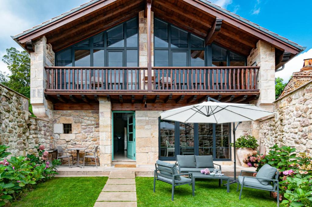 ein Haus mit einer Terrasse und einer Terrasse mit Stühlen und einem Sonnenschirm in der Unterkunft La Casa de Piedra in Herrera de Ibio