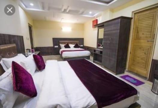 duża sypialnia z 2 łóżkami i fioletowymi poduszkami w obiekcie Vella Marina Group of Hotels w mieście Dharamsala