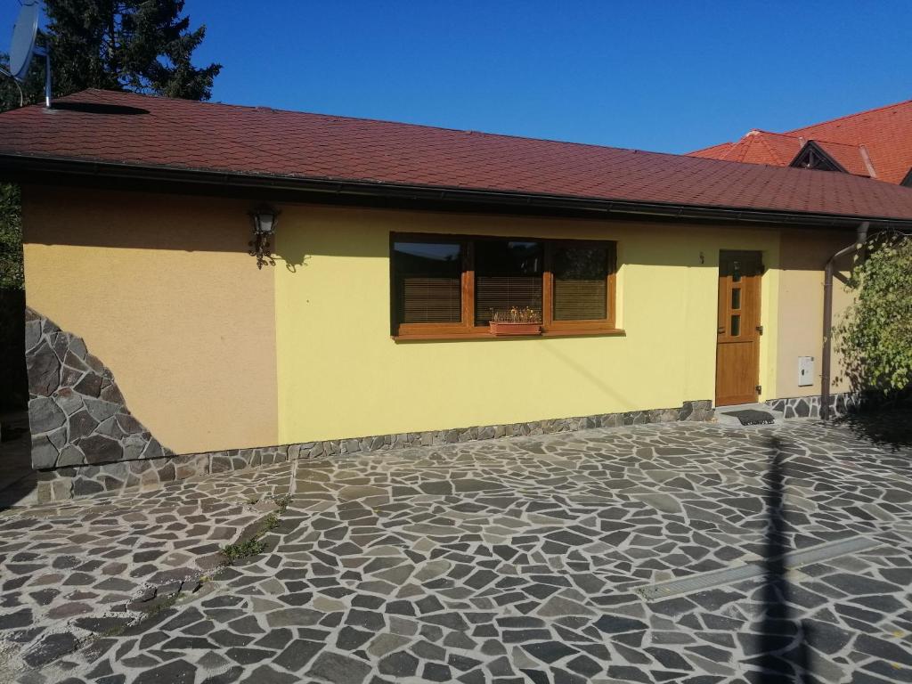 a yellow house with a window and a stone floor at Útulný Domček Privat Bedrich in Poprad