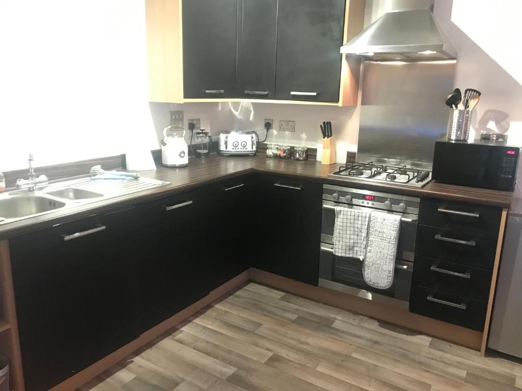 cocina con armarios negros, fogones y fregadero en Stunning 2-Bed Apartment in Newton Abbot en Newton Abbot