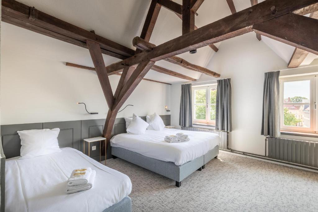 a bedroom with two beds and two windows at Hotel Augustyn Brugge in Bruges