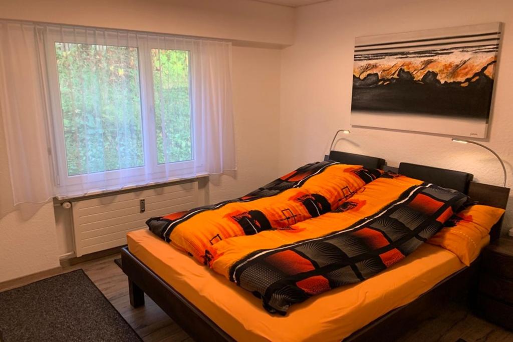 a bed with an orange comforter in a bedroom at Haus Linaria - CharmingStay in Flumserberg