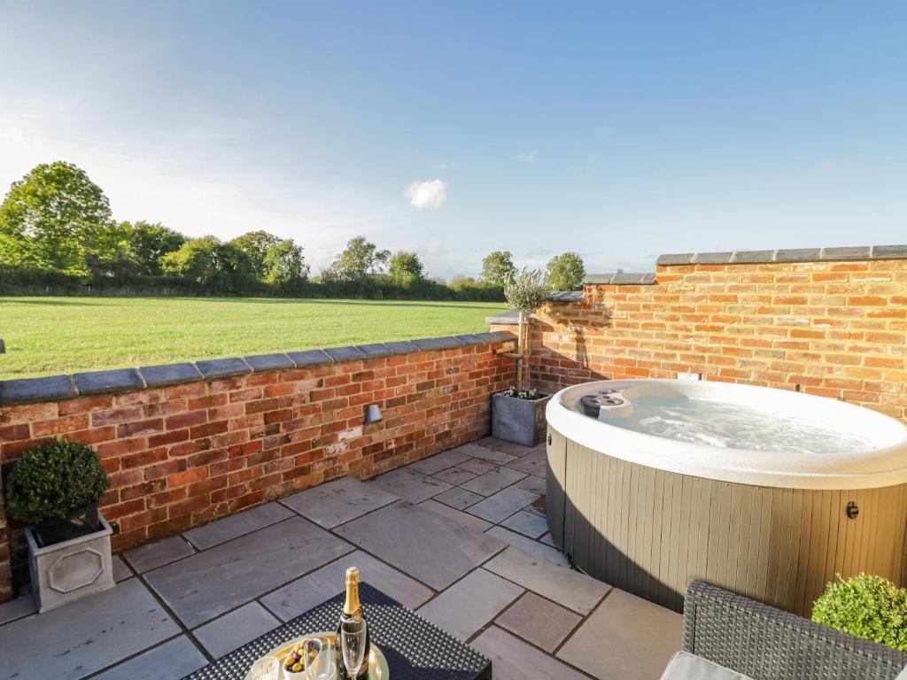 a hot tub on a patio with a brick wall at The Hyde in Stratford-upon-Avon