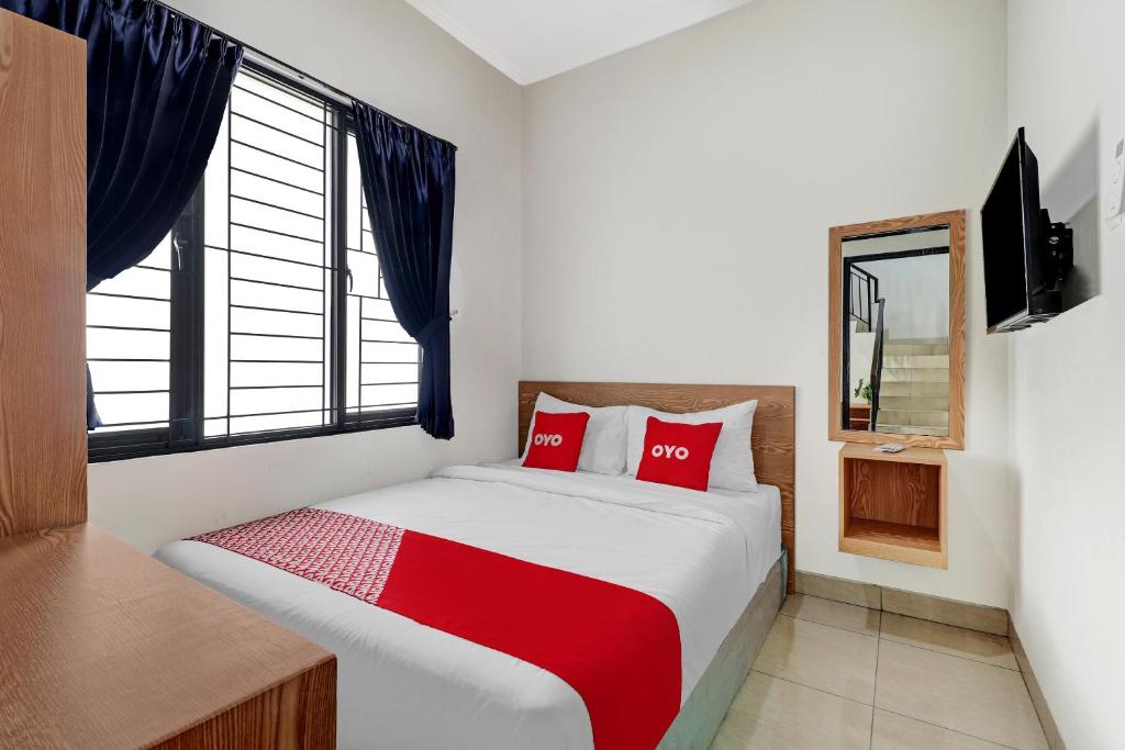 Un dormitorio con una cama con almohadas rojas y una ventana en OYO 90688 Marta Residence, en Karawang