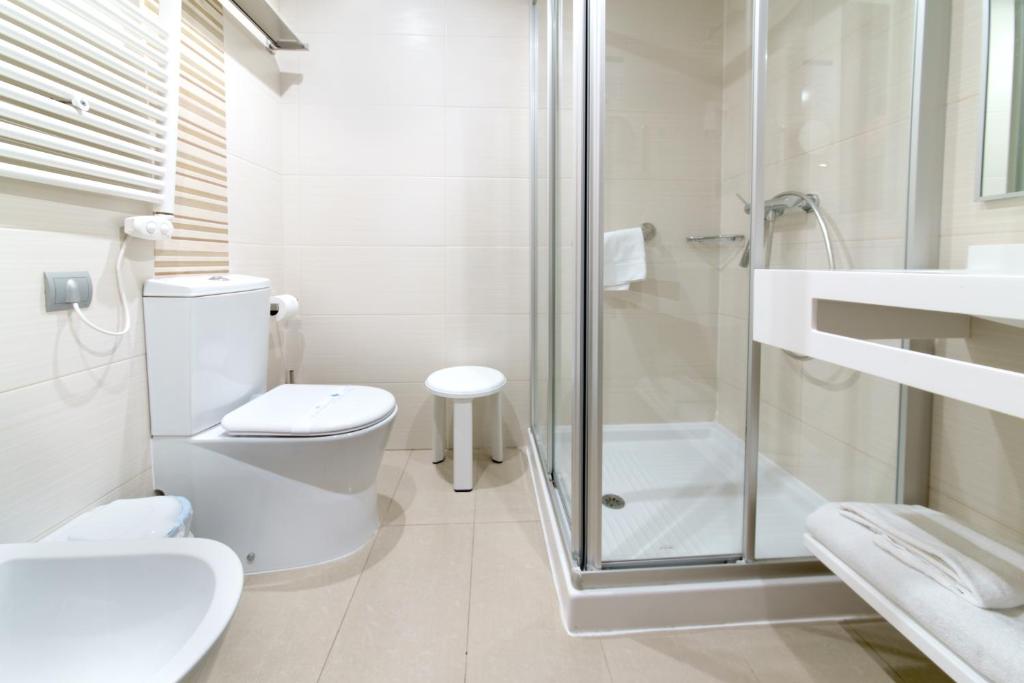 a white bathroom with a toilet and a shower at Hotel Porto Calpe in Calpe