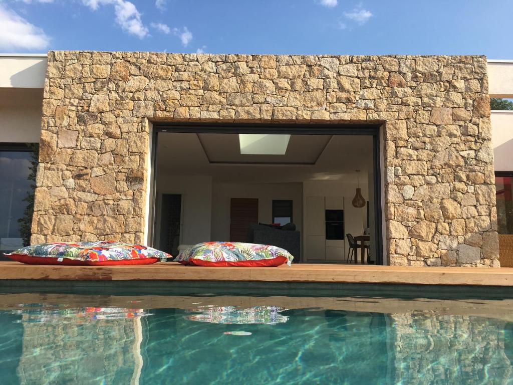 a swimming pool with two pillows next to a stone wall at Villa Alandra in Pietrosella
