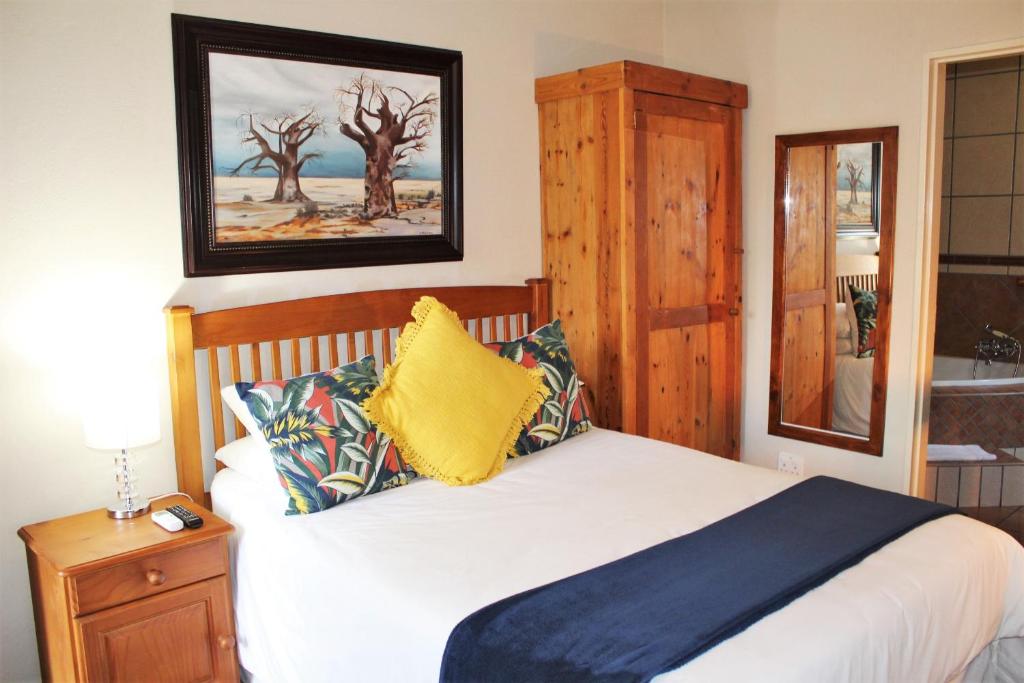 a bedroom with a bed with a yellow pillow at Ngwenya Boutique Hotel in Lephalale
