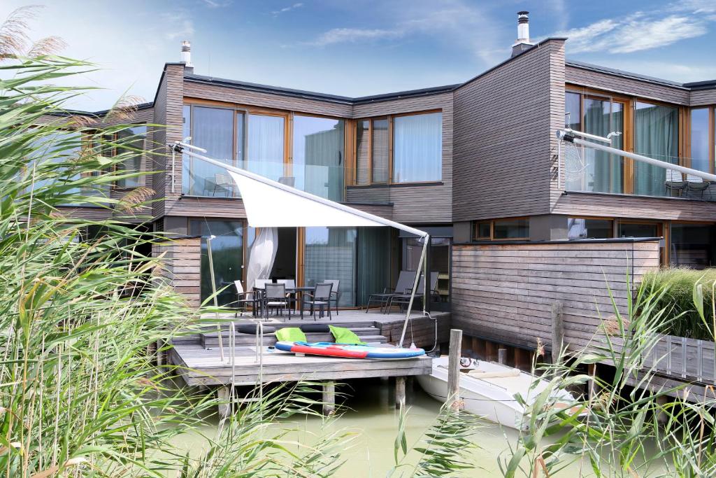 a house on the water with a table and chairs at Seehaus LakeSide - Am Hafen in Neusiedl am See