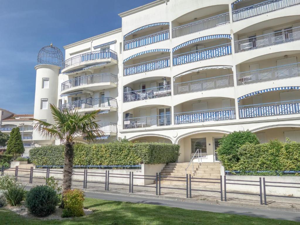 a white building with a palm tree in front of it at Apartment Parc de Pontaillac-10 by Interhome in Pontaillac