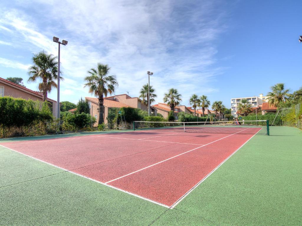 un court de tennis avec des palmiers en arrière-plan dans l'établissement Holiday Home Le Clos de St Cyprien-5 by Interhome, à Saint Cyprien Plage