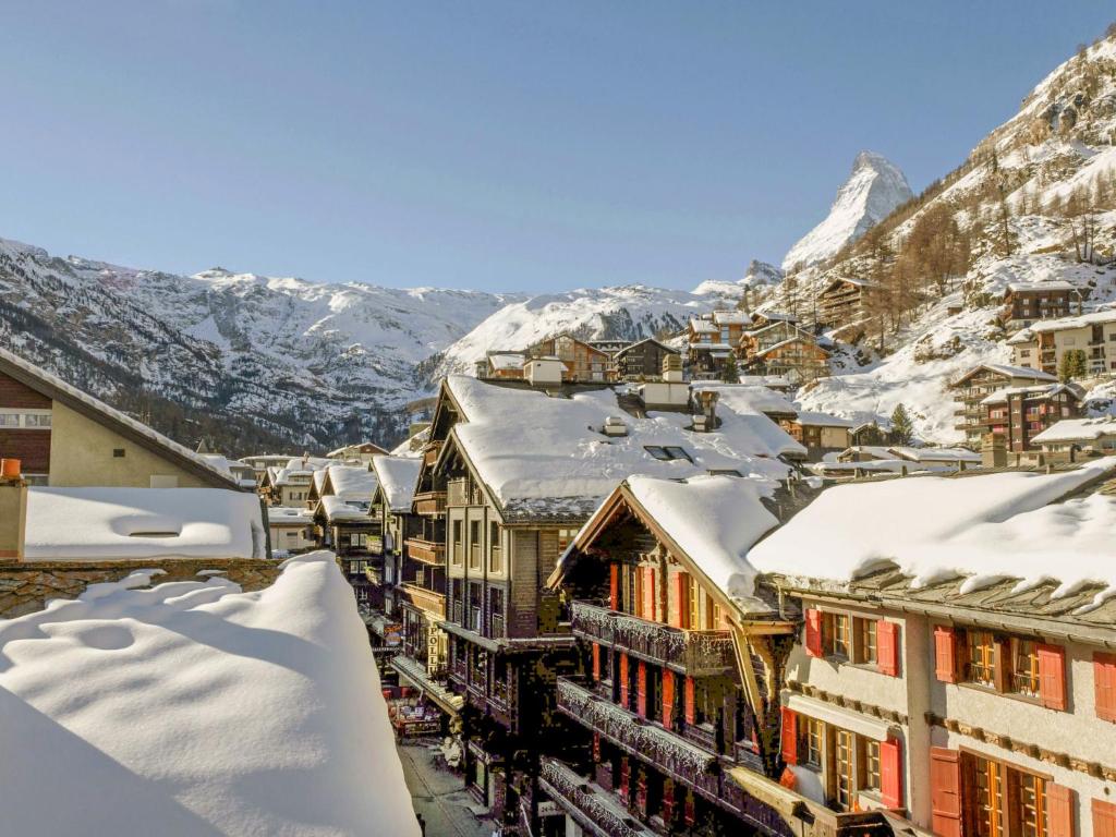 una ciudad cubierta de nieve con montañas en el fondo en Apartment Center by Interhome, en Zermatt