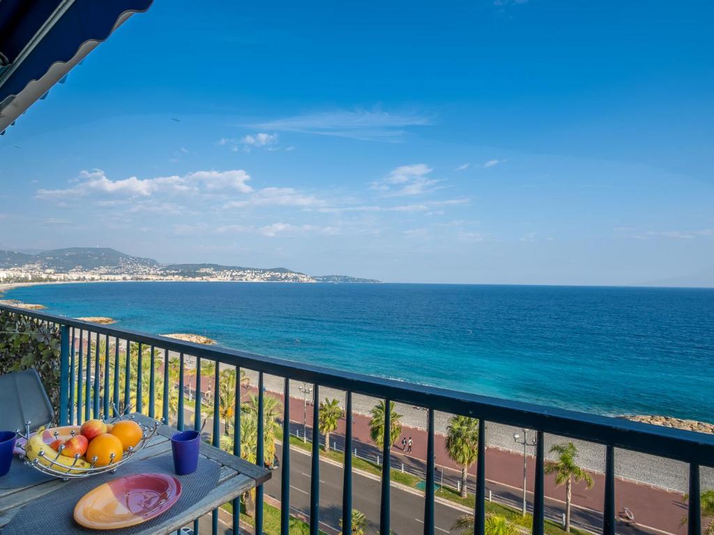 a table with a bowl of fruit on a balcony overlooking the ocean at Apartment Copacabana Promenade des Anglais by Interhome in Nice