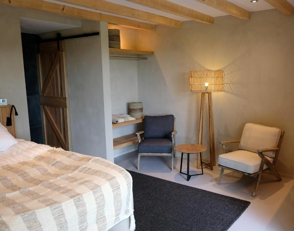 a bedroom with a bed and two chairs and a lamp at Bed & Wijn - Suite 2 in Staphorst