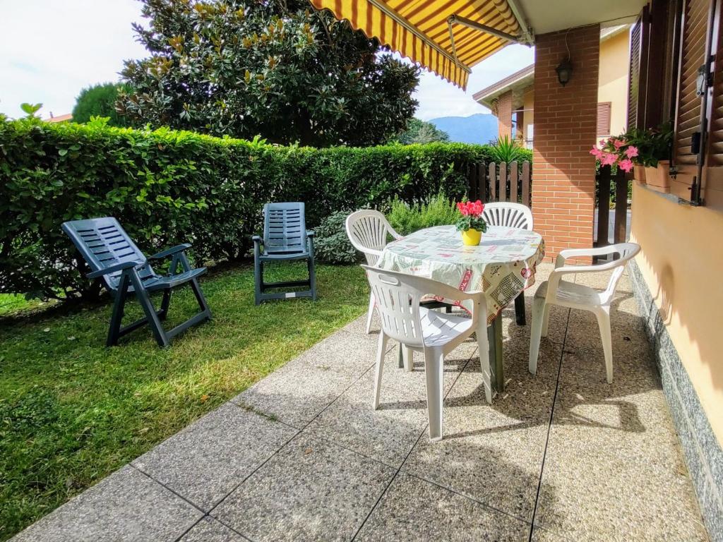 patio z krzesłami i stołem z kwiatami w obiekcie Apartment Parco Musadino by Interhome w mieście Porto Valtravaglia