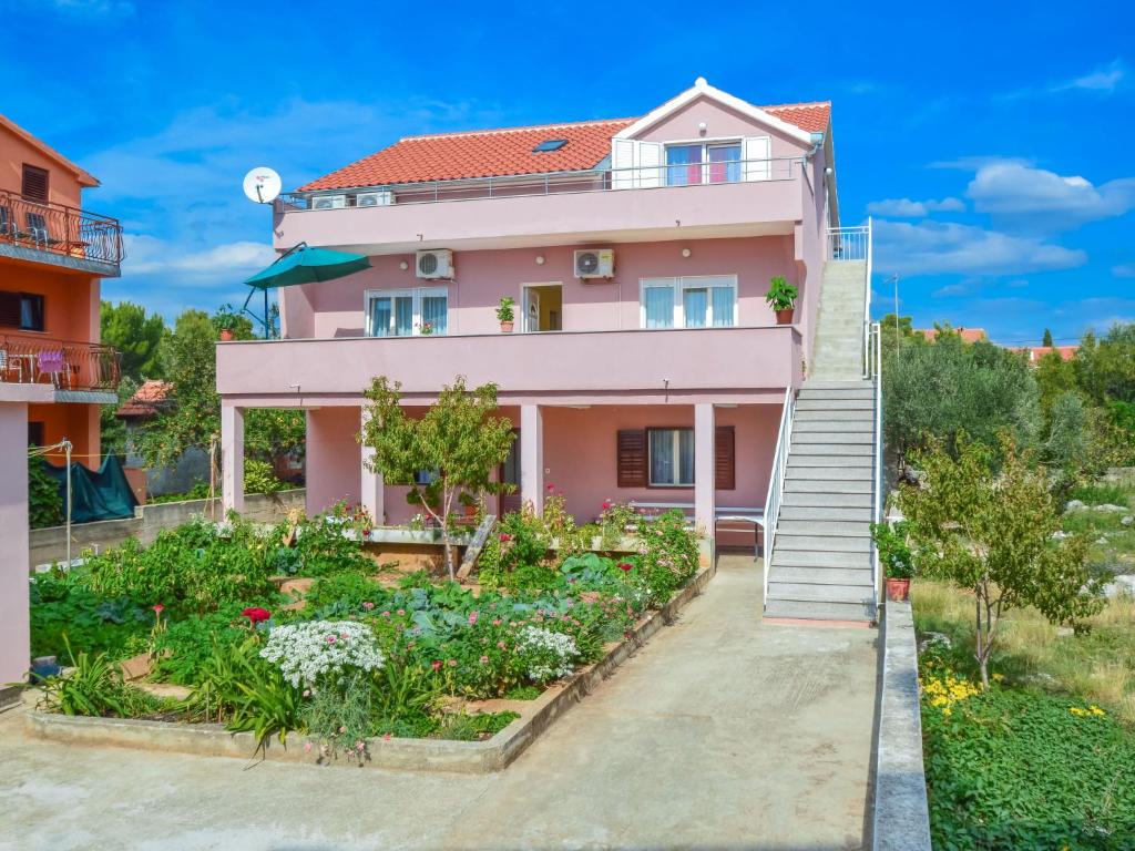 une maison rose avec un jardin devant elle dans l'établissement Apartment Šime by Interhome, à Brodarica