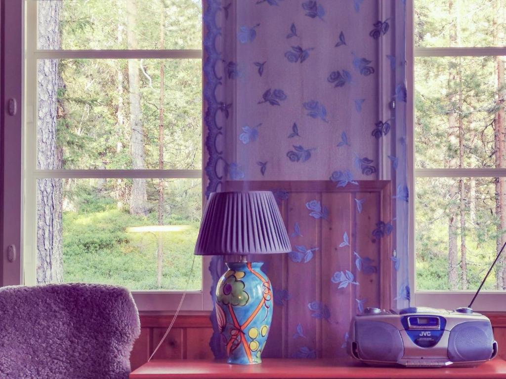 eine Lampe auf einem Tisch neben einem Fenster in der Unterkunft Holiday Home Käenkukka in Luosto