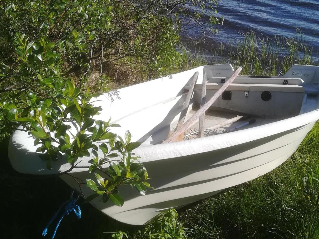 a white boat sitting on the grass next to the water at Holiday Home Pikkupöllö in Kaaresuvanto