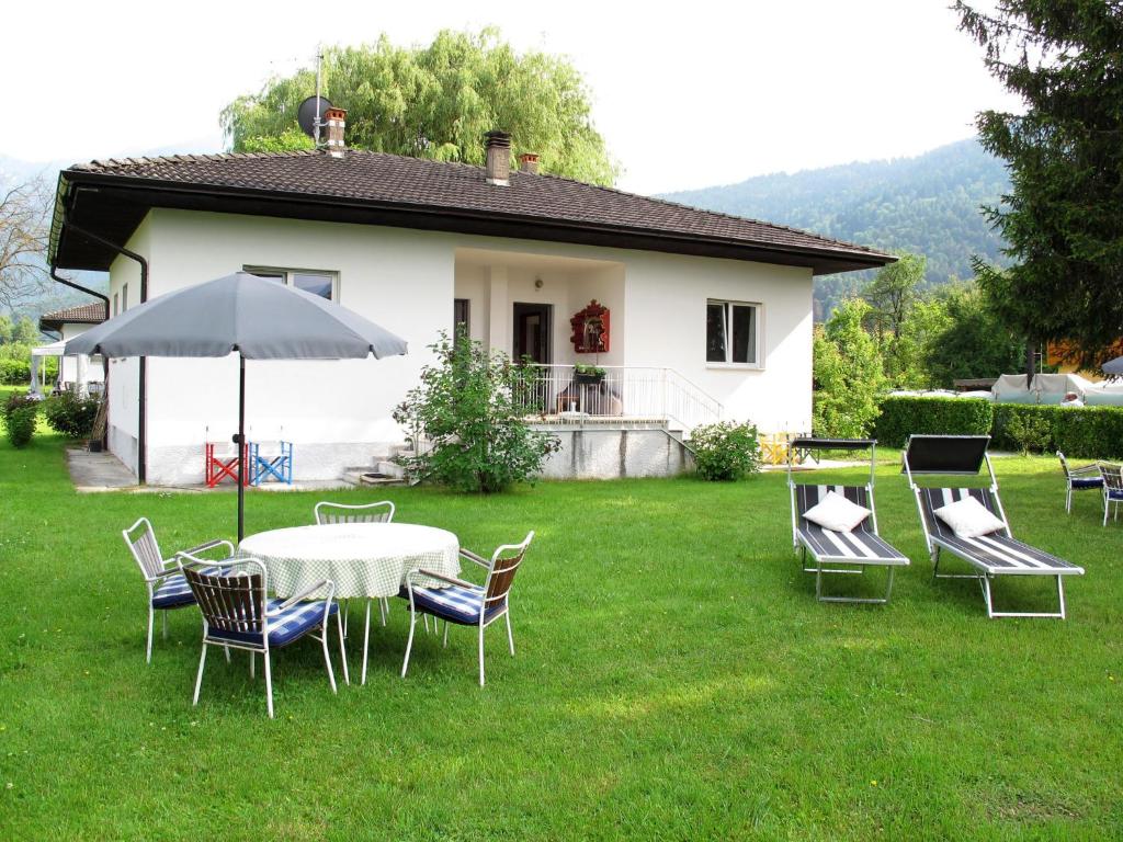 einen Tisch mit Stühlen und einen Regenschirm im Hof in der Unterkunft Holiday Home Villetta ai Pini-1 by Interhome in Calceranica al Lago