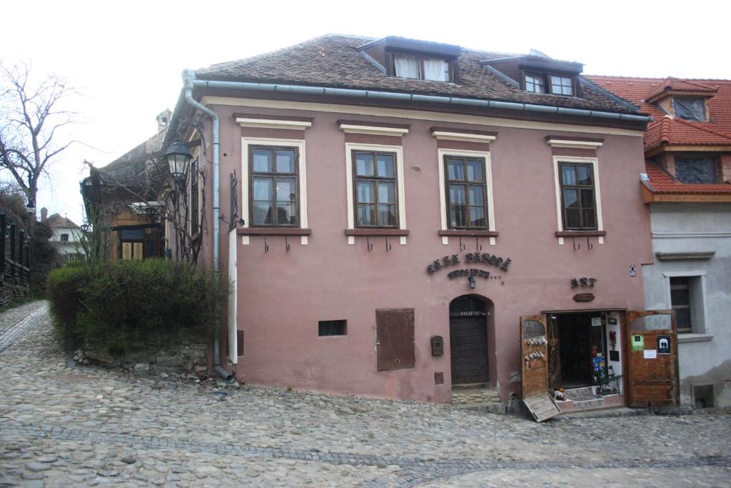 a pink house sitting on a cobblestone street at Casa Baroca in Sighişoara