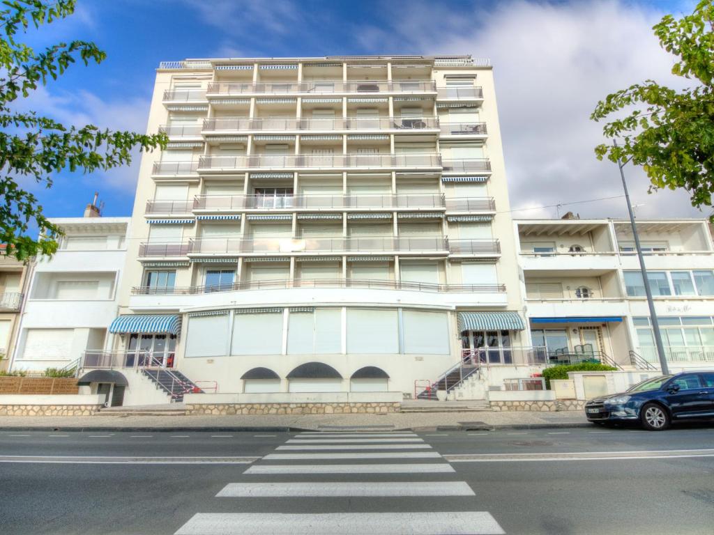 a tall white building with a car parked in front of it at Apartment Les Autans by Interhome in Royan