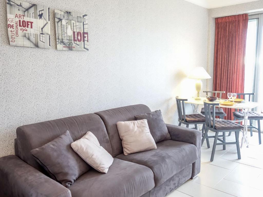 a living room with a brown couch and a table at Apartment Les Autans by Interhome in Royan