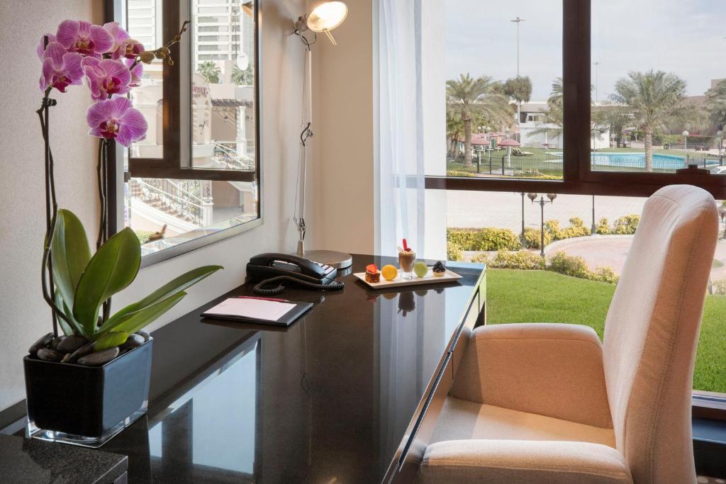 an office with a desk with a phone and a flower at Crowne Plaza Bahrain by IHG in Manama