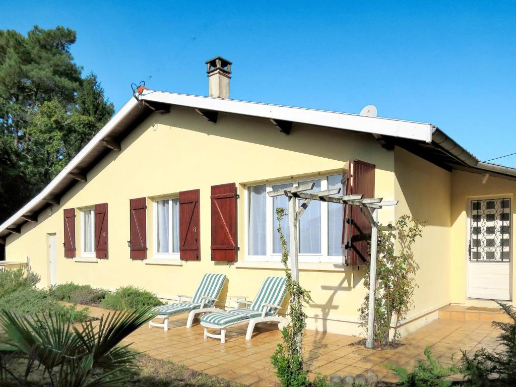 une maison jaune avec 2 chaises sur une terrasse dans l'établissement Holiday Home Les Hirondelles by Interhome, à Andernos-les-Bains