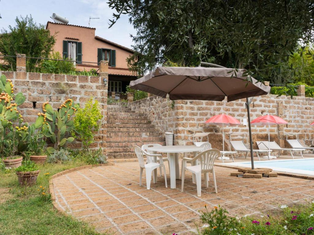 - une table et des chaises avec un parasol à côté de la piscine dans l'établissement Holiday Home Casale Ai Noccioli - LVC165 by Interhome, à Corchiano