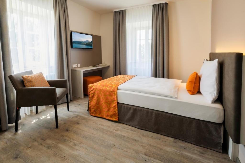 a hotel room with a bed and a chair at Hotel Kurhaus Bad Bocklet in Bad Bocklet