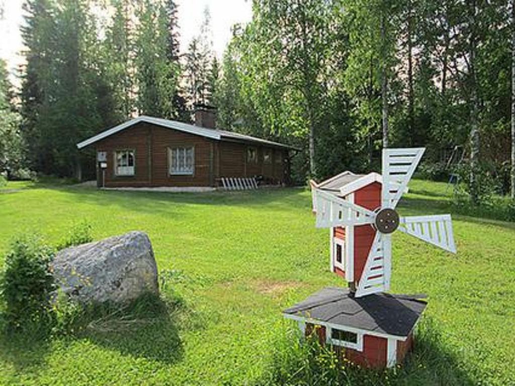 ein kleines Haus mit einer Windmühle in einem Hof in der Unterkunft Holiday Home Taukotupa by Interhome in Höytee