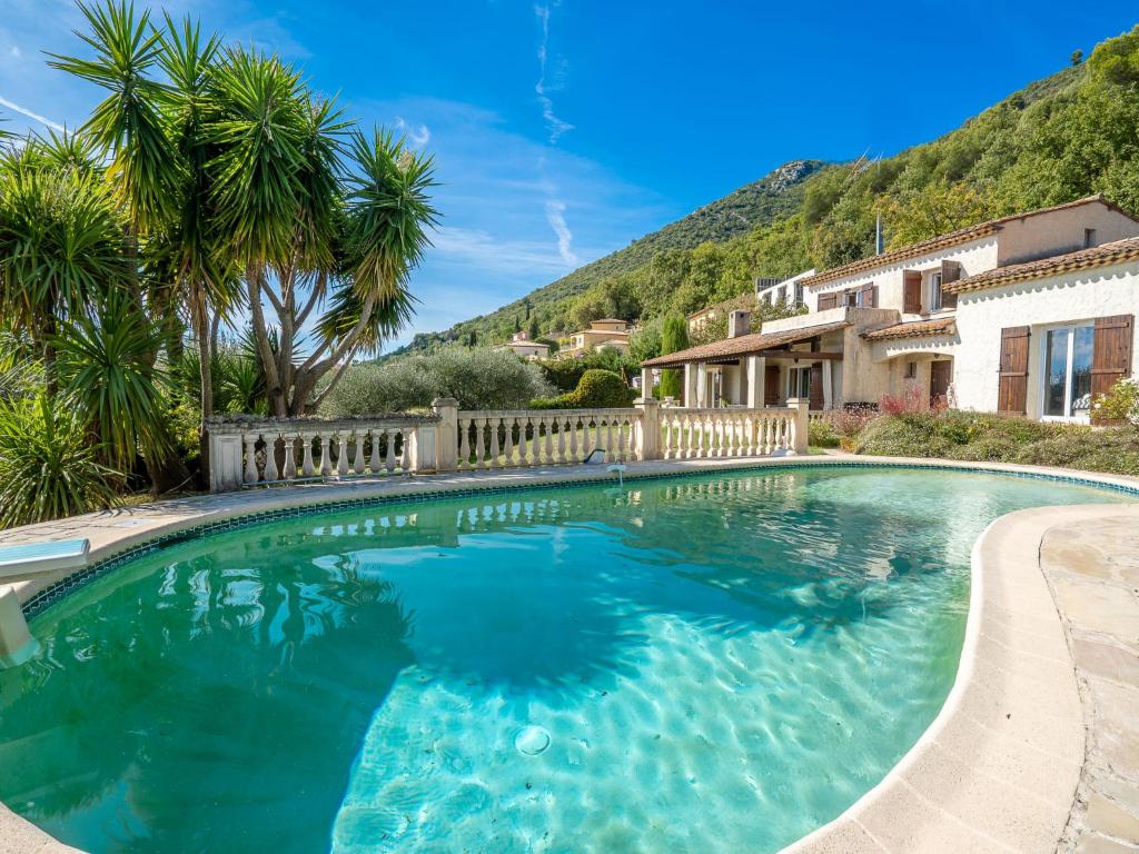 uma piscina com água azul e palmeiras em Holiday Home La Mesnière by Interhome em Gattières