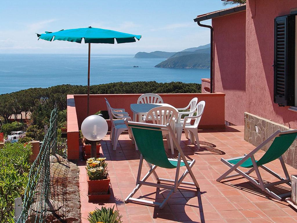 un patio con mesa, sillas y sombrilla en Apartment Palma by Interhome en Capoliveri
